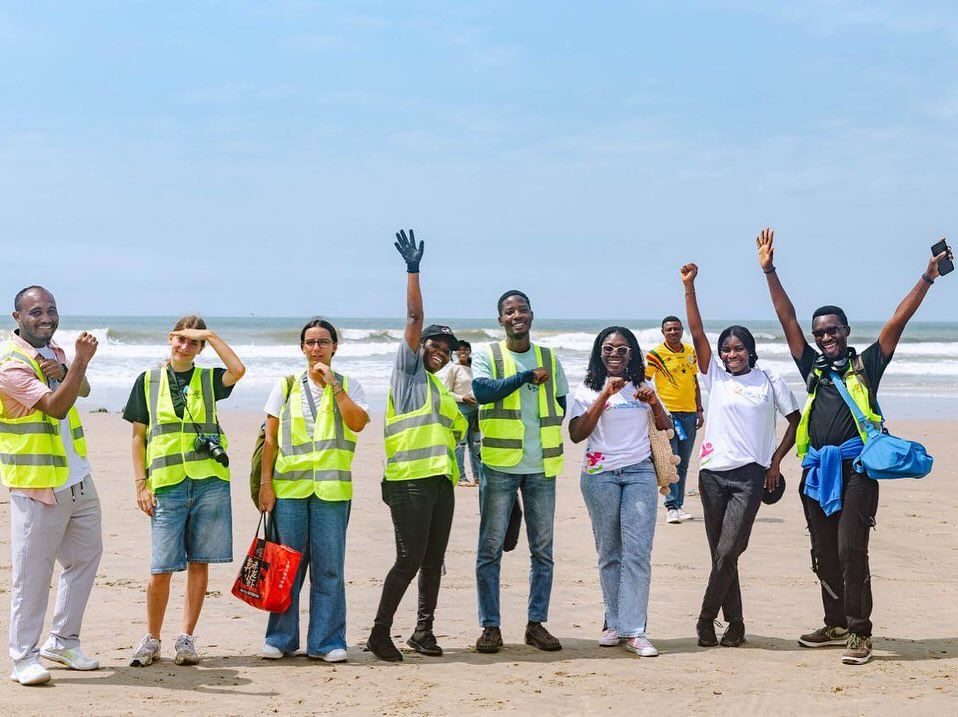 Volunteers in high-visibility vests celebrating after a beach clean-up